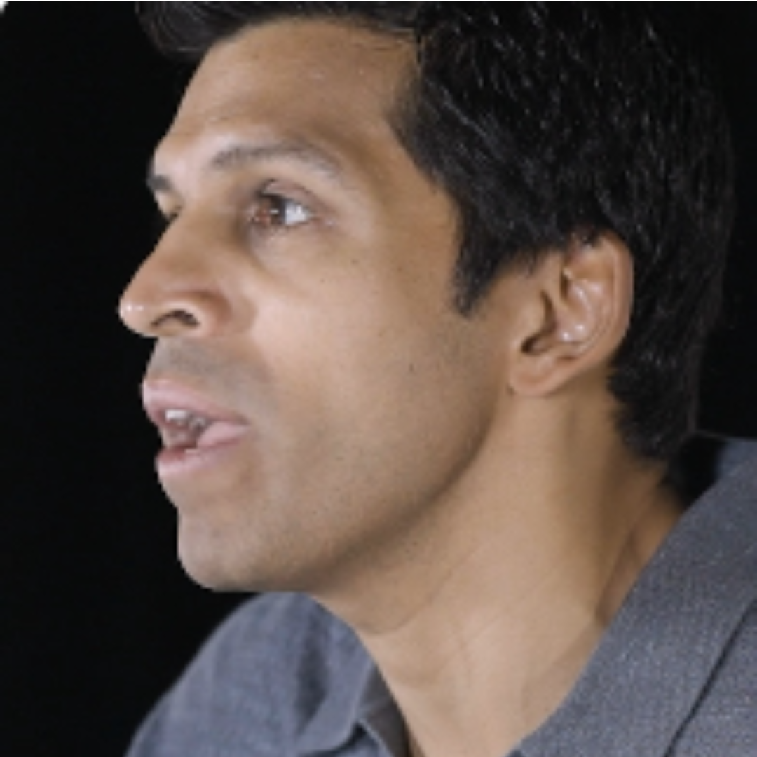 Side profile photo of Ronnie Chatterji wearing a grey polo shirt and speaking.