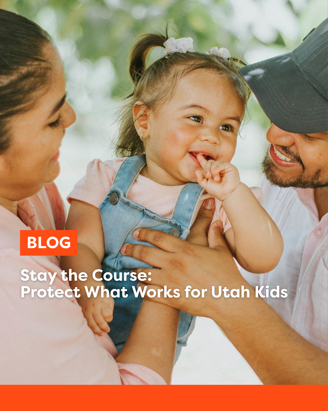 Mom and dad holding young smiling female toddler. 