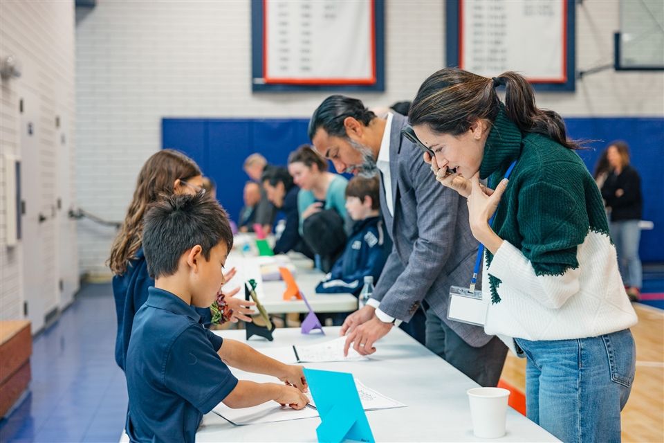 A Grade 2 student presents their booklet to a parent during the Pieces of Me Showcase