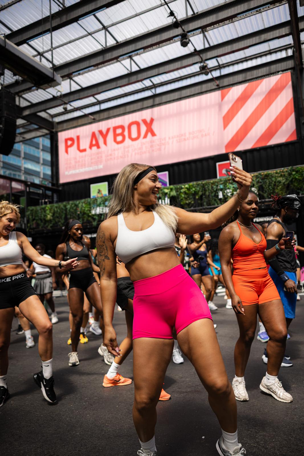 woman wearing pink gym apparel taking selfie at fitness event